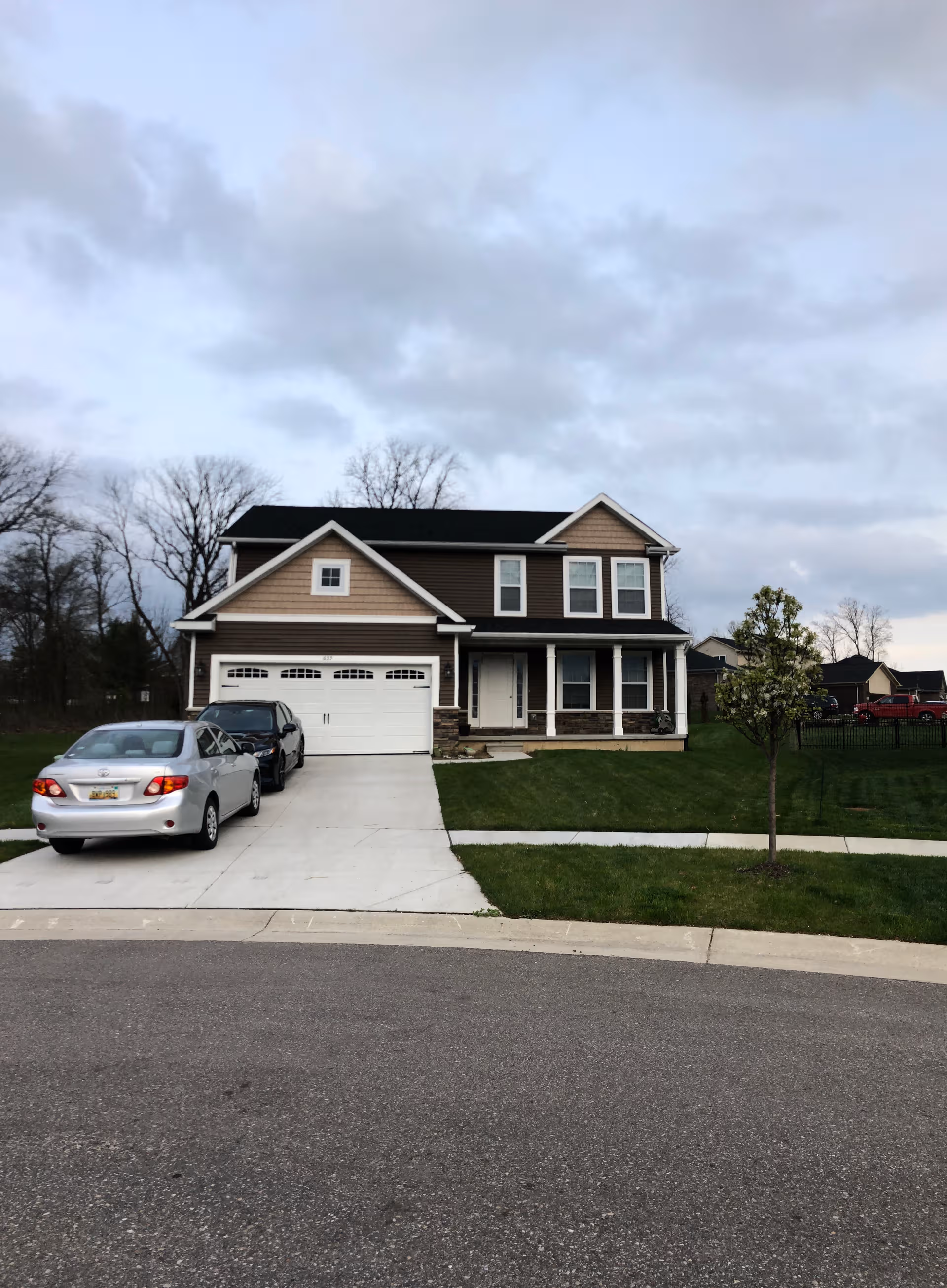 Two cars parked in a driveway in front of a two-story suburban house.
