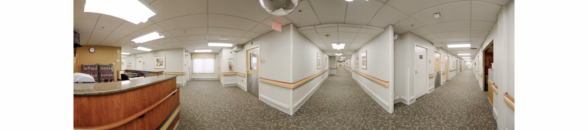 Wide corridor with a reception desk on the left and doors lining both sides.