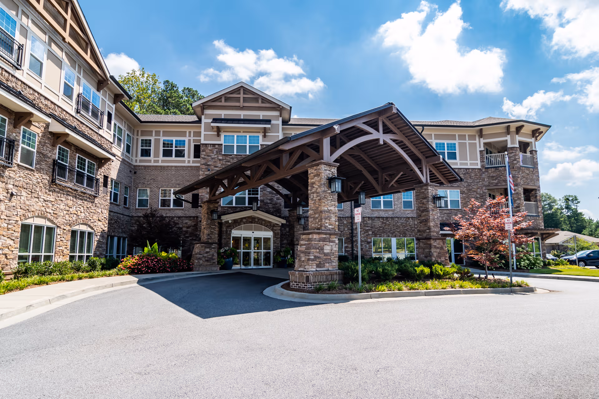 Exterior view of Arbor Terrace Burnt Hickory with stone facade, porte-cochère, and driveway entry.