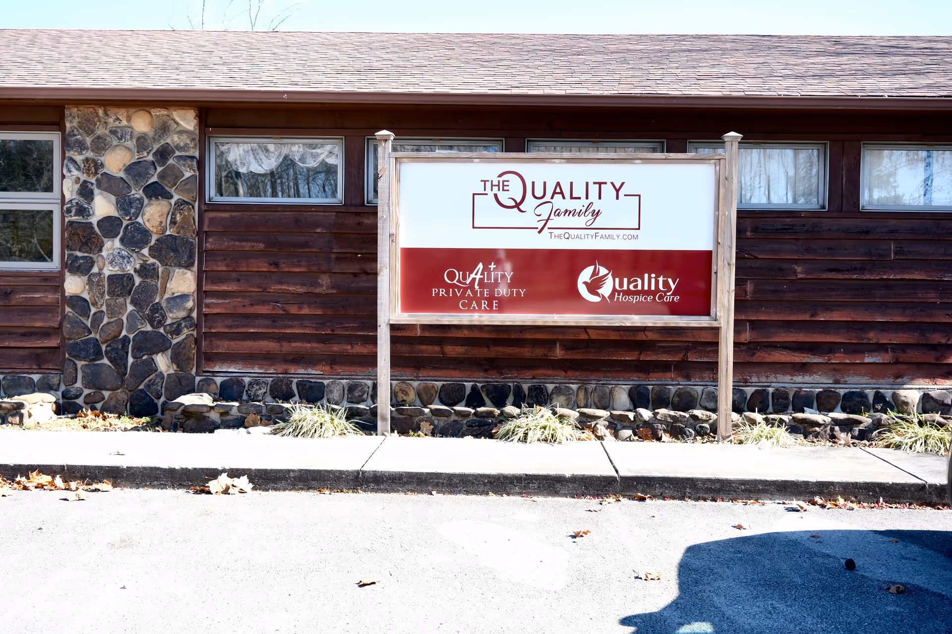 Exterior view of a wooden building with a large sign advertising Quality Private Duty Care.