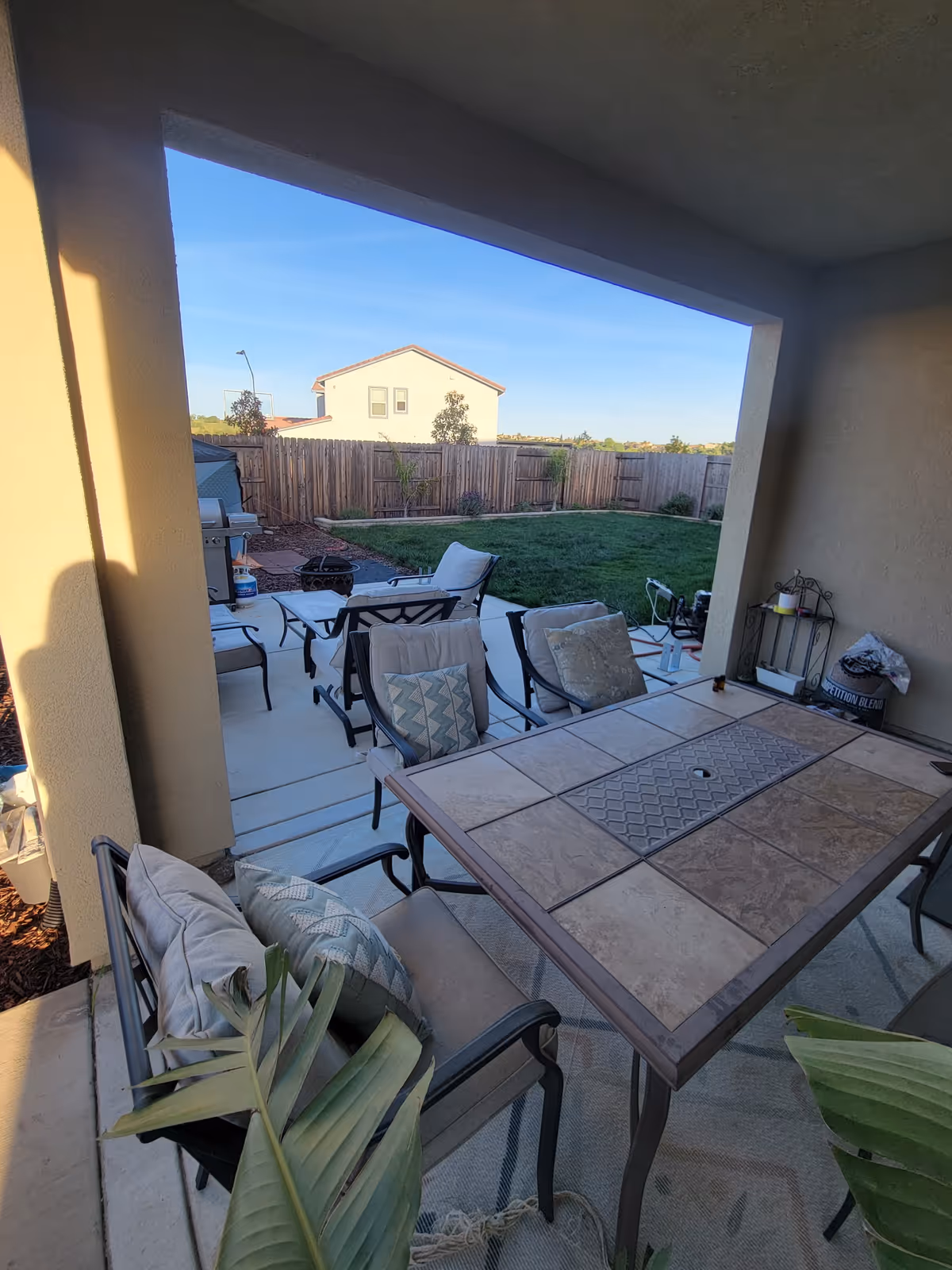 Covered patio with seating area and fenced backyard beyond.