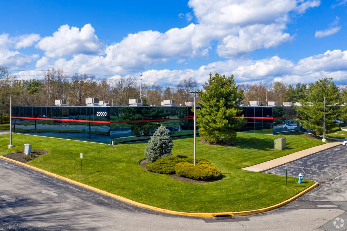 Wide exterior view of a glass-front building with manicured lawn and trees.