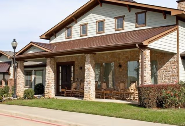 Front view of Magnolia Court Assisted Living building with stone columns and a porch.