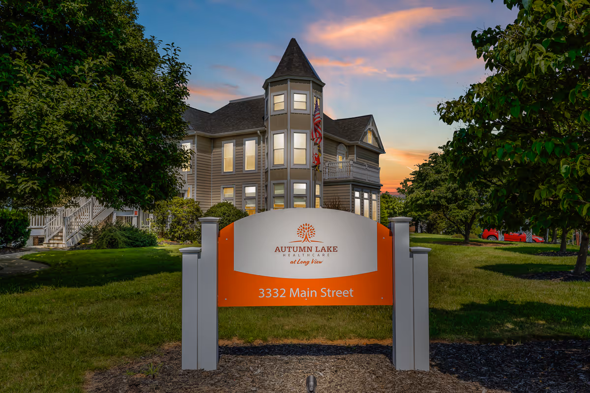 Sign for Autumn Lake Healthcare at Long View (3332 Main Street) in front of a Victorian-style building at sunset.