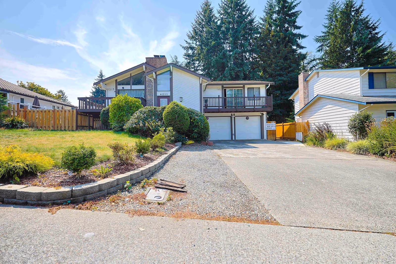 Two-story building with a driveway, two garages, and a landscaped front yard.