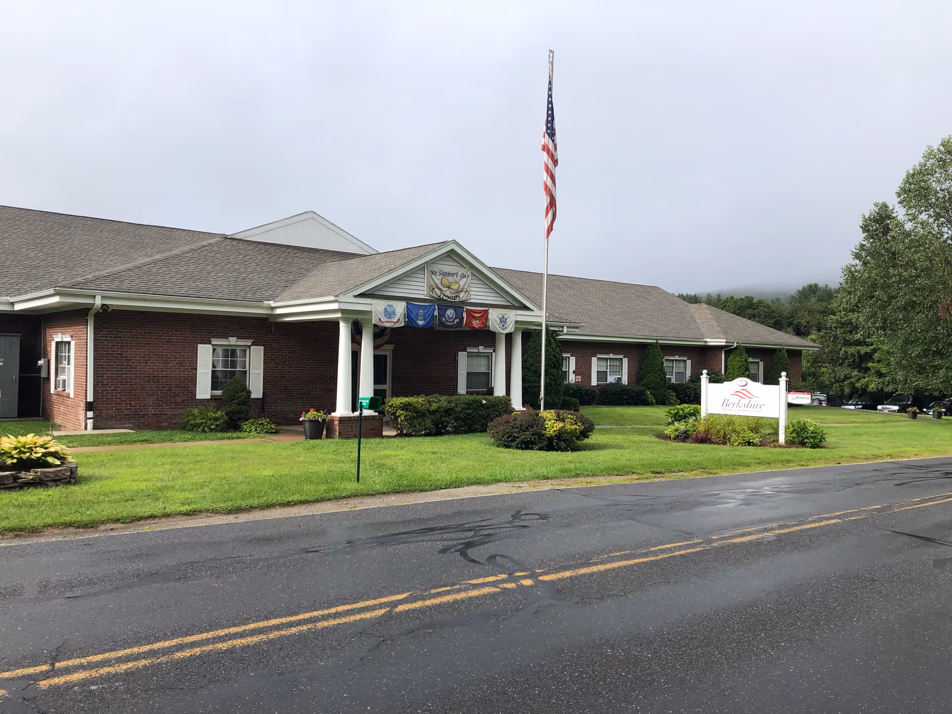 Exterior view of Berkshire Health Care Center with flagpole and manicured lawn.