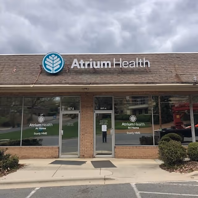 Brick storefront with Atrium Health At Home Stanly signage and glass entry doors