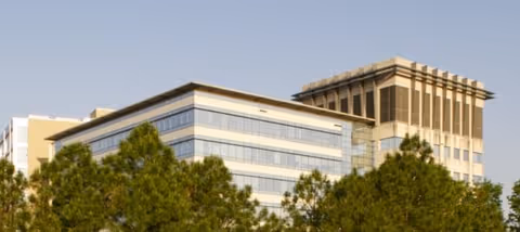 Exterior view of a modern cancer care tower with glass windows and trees.