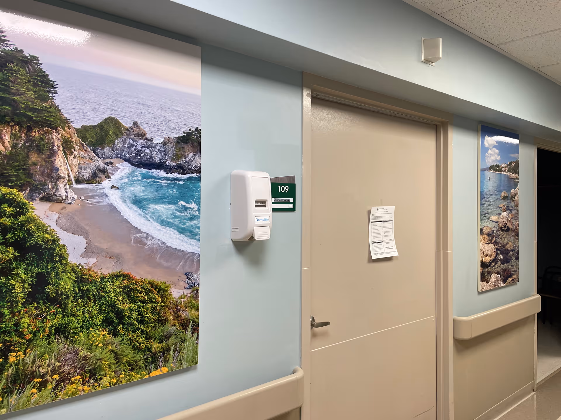 Interior hallway of Cassena Care at Stamford with a beige door and coastal wall art.