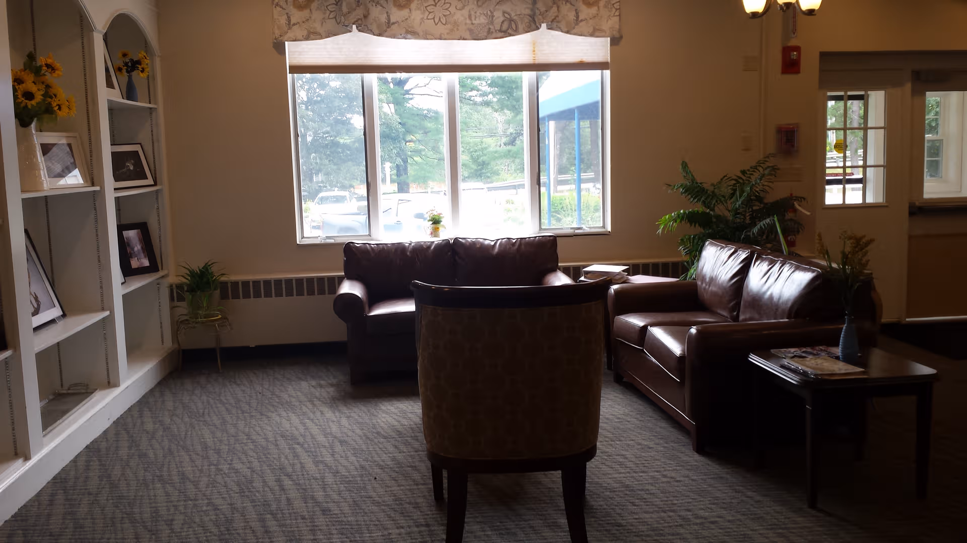 Cozy lounge area in a senior facility with leather sofas, chairs, and window view.