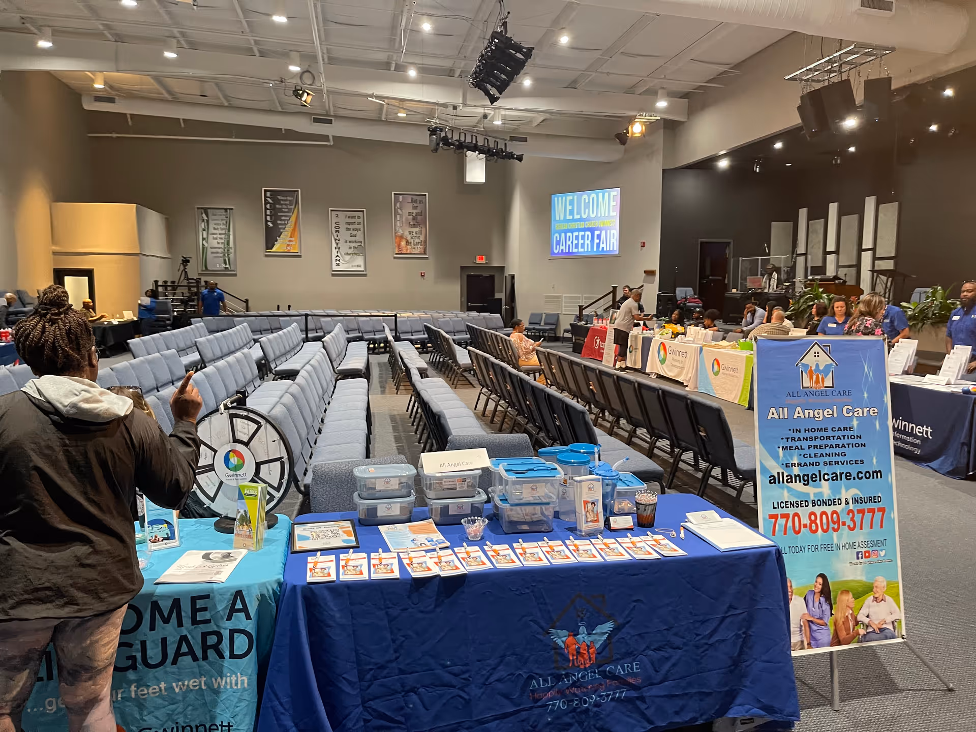 A large indoor hall set up for a career fair, with vendor tables and banners.