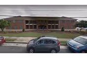 Exterior front view of St. Francis Home with entrance and parked cars.