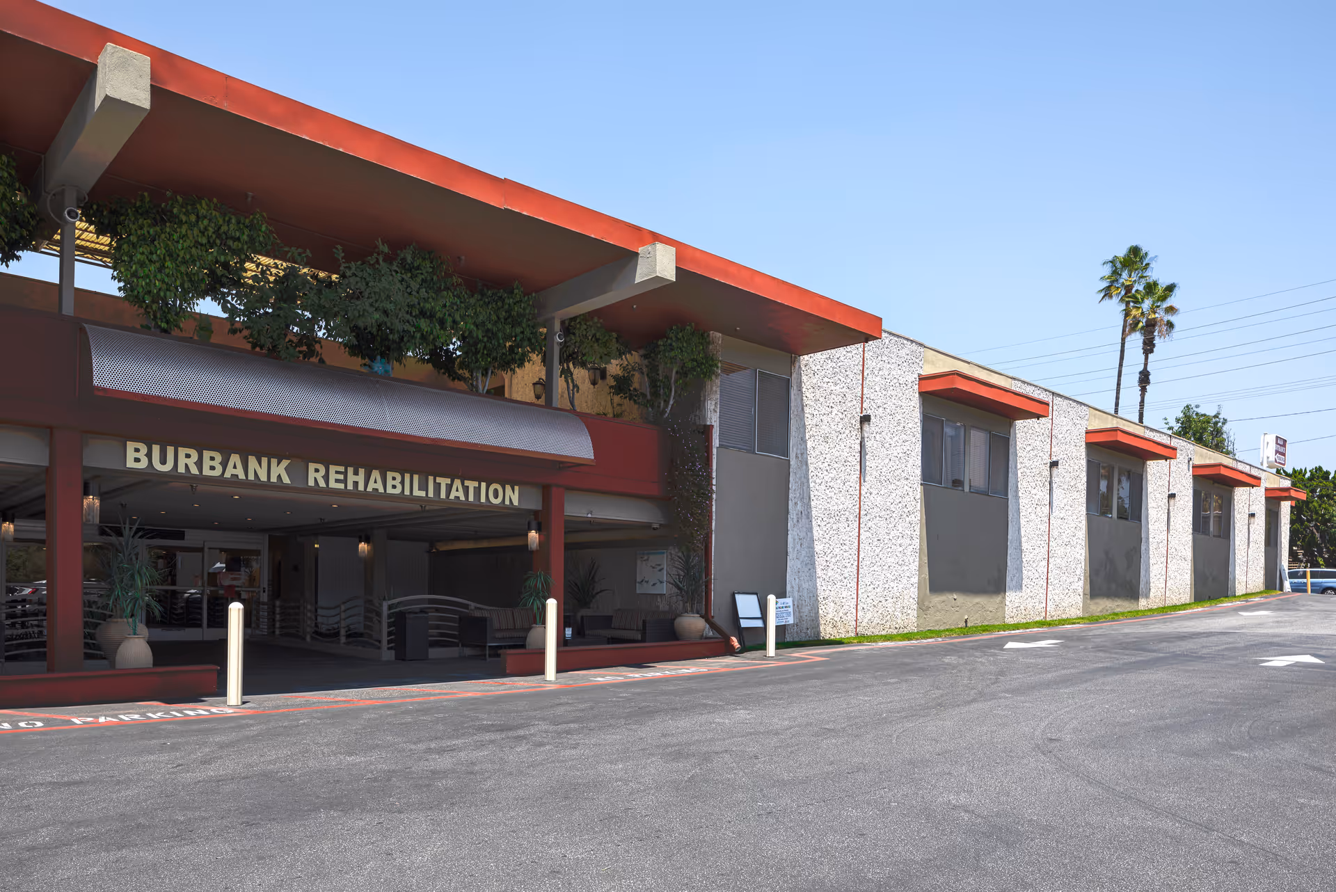 Exterior view of Burbank Rehabilitation building with red trim and covered entrance.