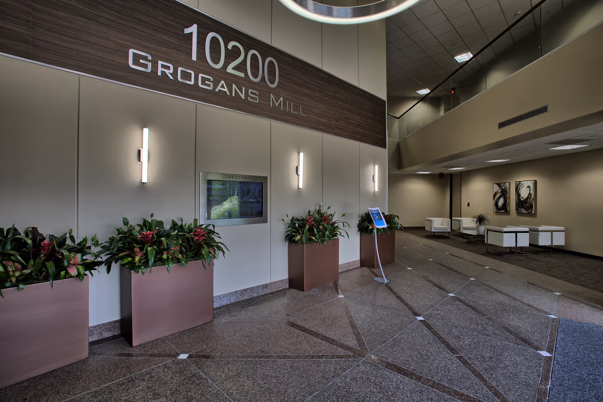 Modern interior lobby with planters, signage, and seating in a spacious hallway.