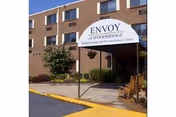 Brick senior living building with curved awning and Envoy of Woodbridge entrance sign.