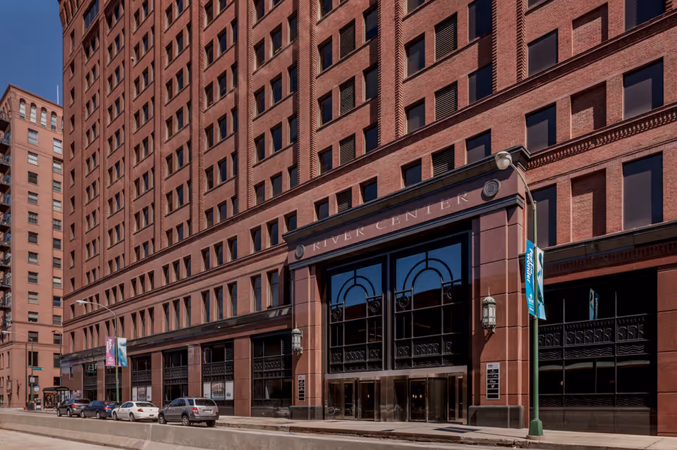 Brick high-rise building with arched glass entrance along a busy city street