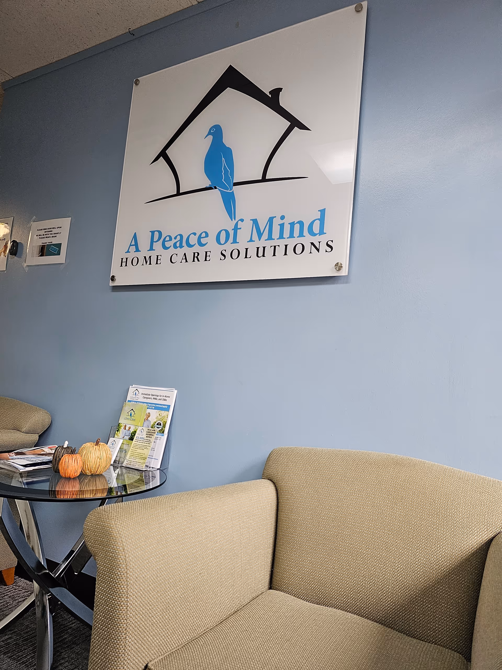 Interior lobby with blue wall, beige chair, glass table, and sign 'A Peace of Mind'.