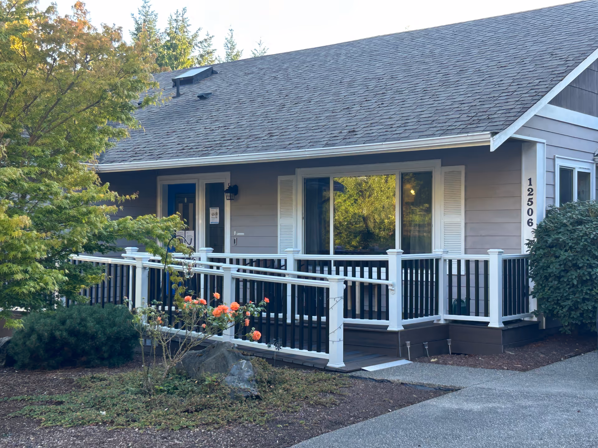 Front view of a single-story senior care home with a wooden porch and railing.