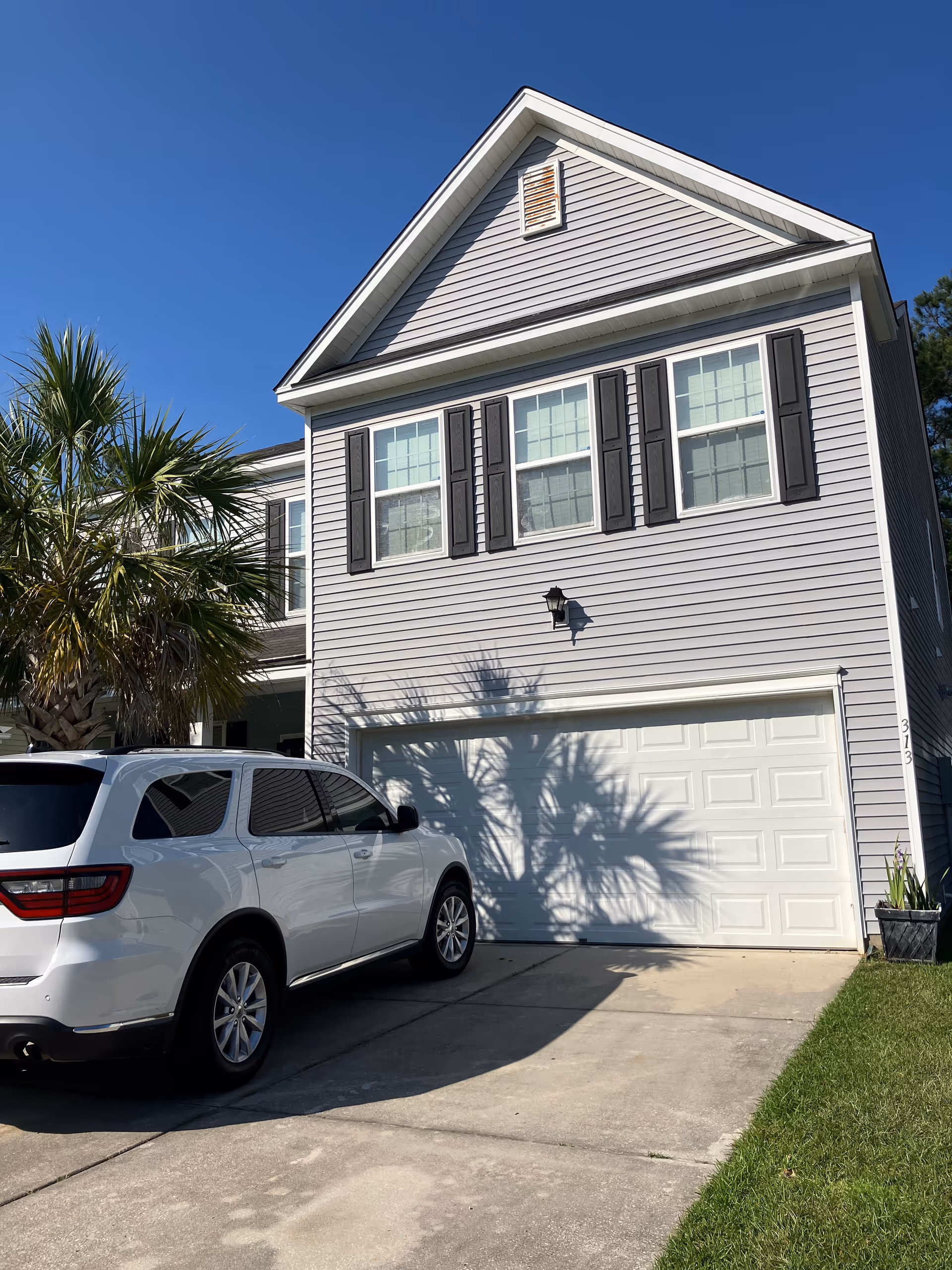 Front view of a gray two-story house with a garage and white SUV.