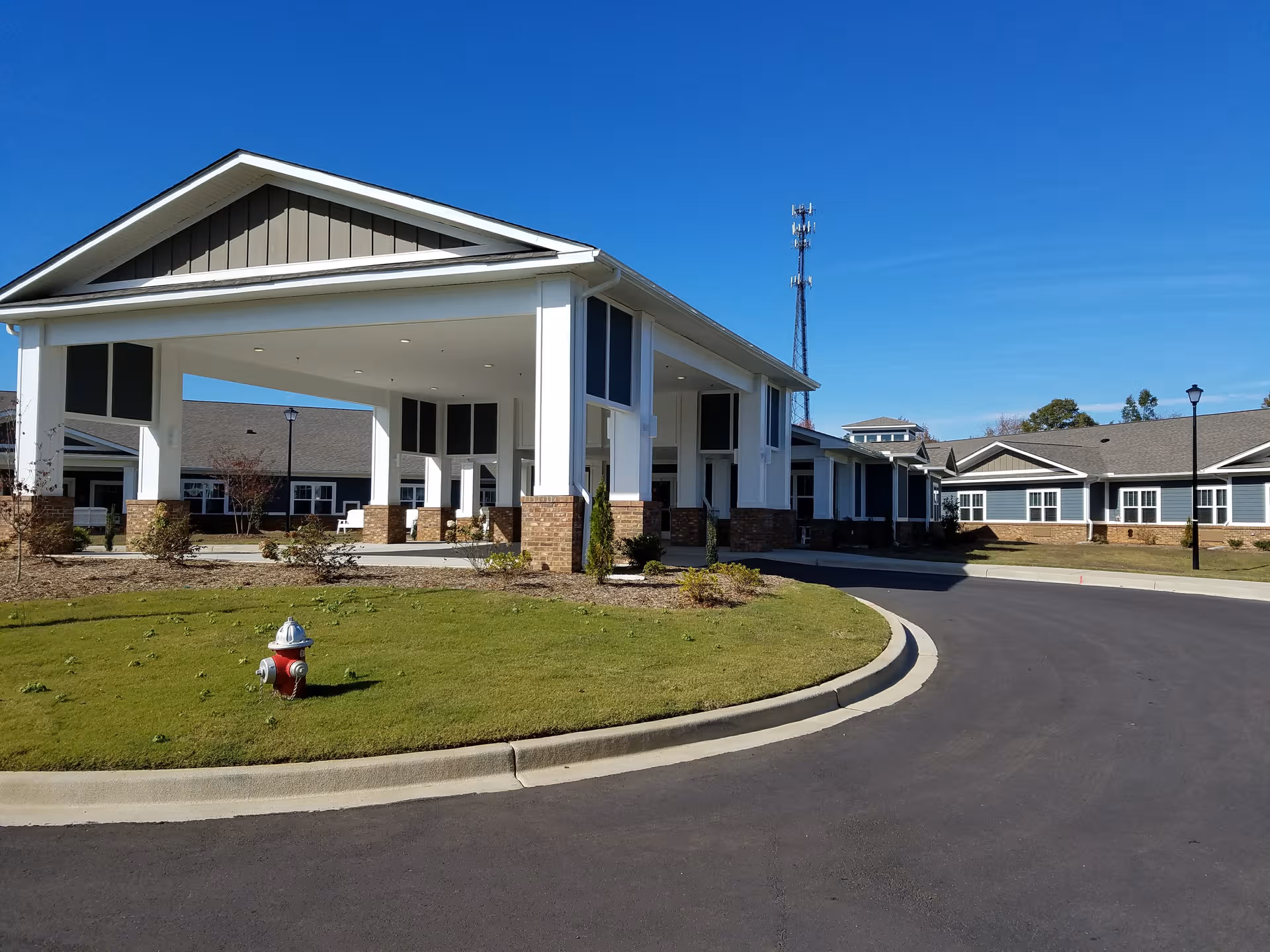 A modern assisted living center with a covered entrance and circular driveway on a sunny day.