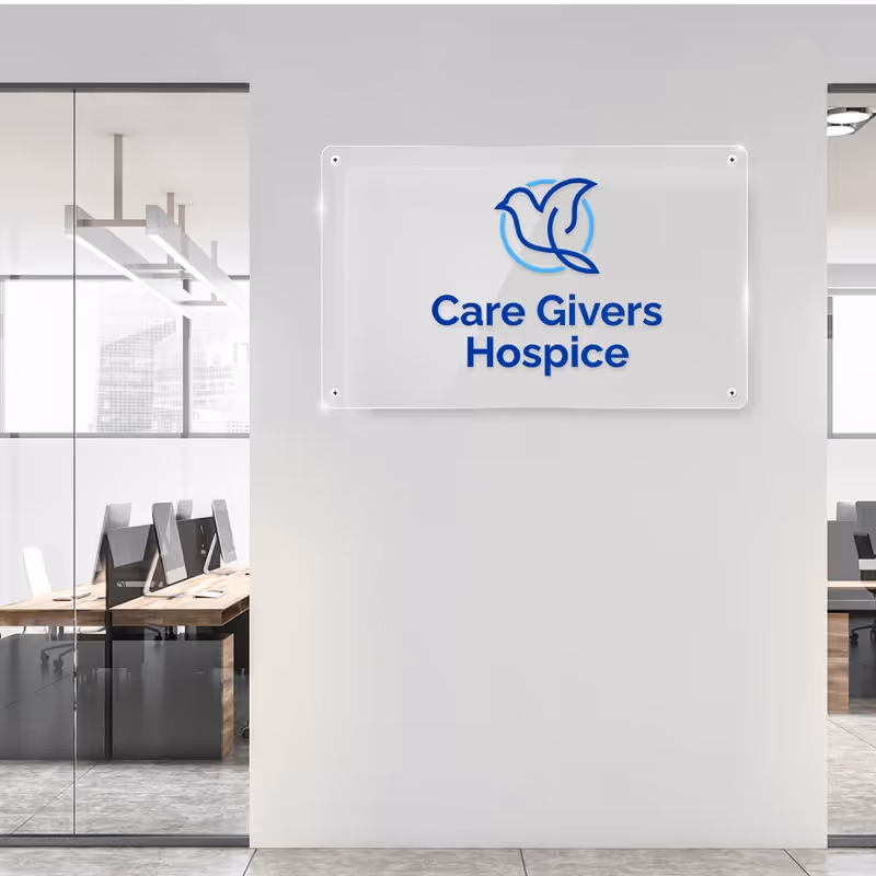 White wall with a Care Givers Hospice sign and glass-walled offices in a modern lobby.