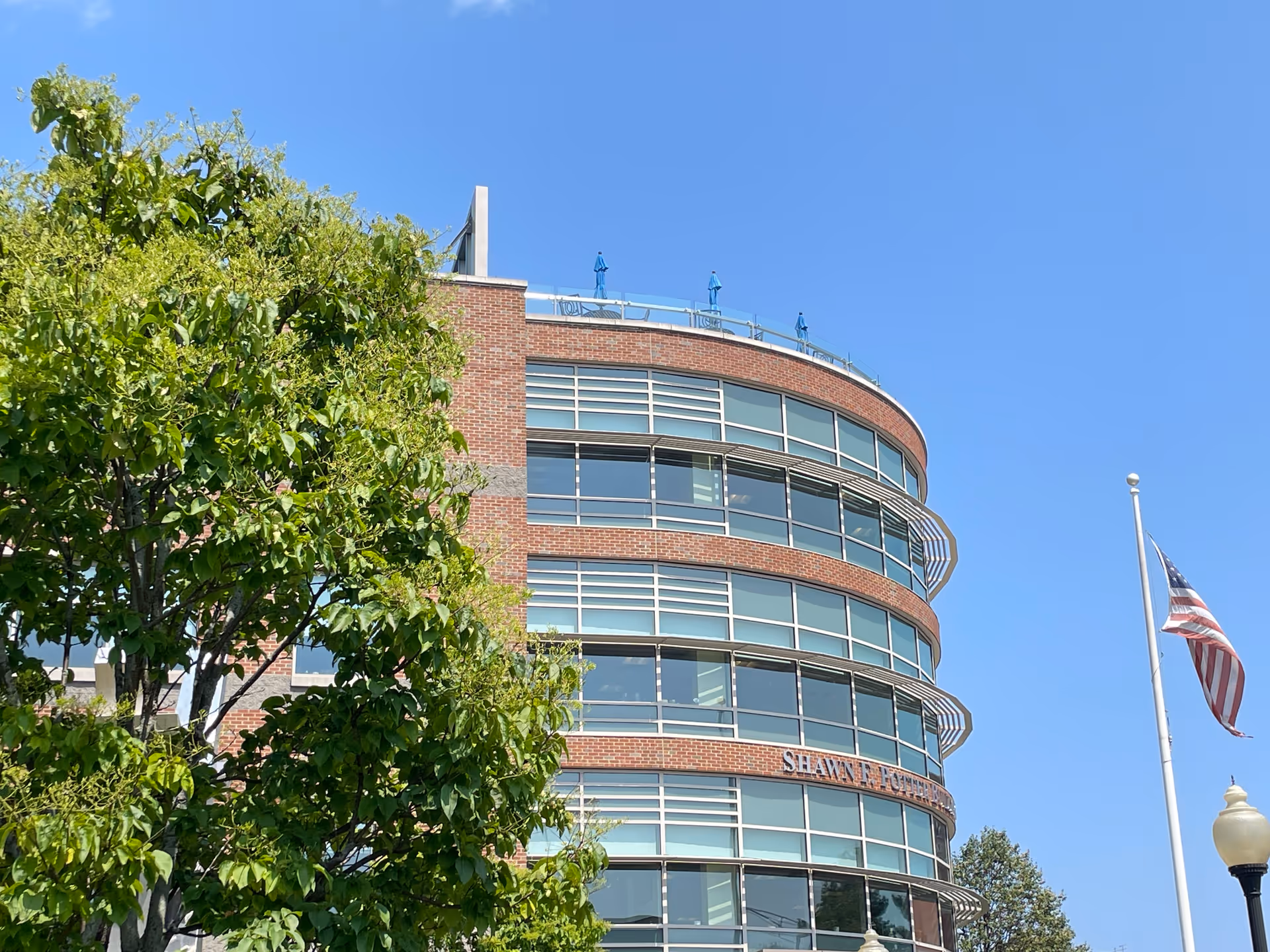Curved brick and glass exterior of a multi-story senior living facility with a flag.