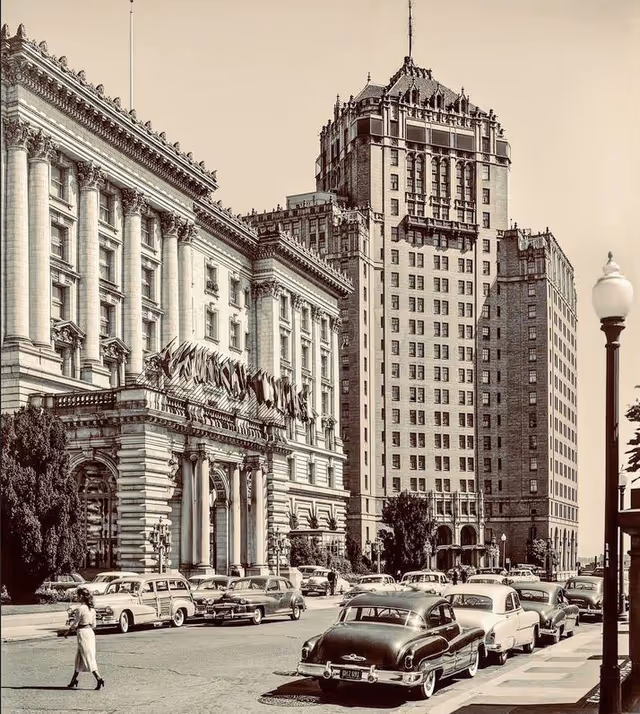 Historic city street with vintage cars and a grand ornate building facade.