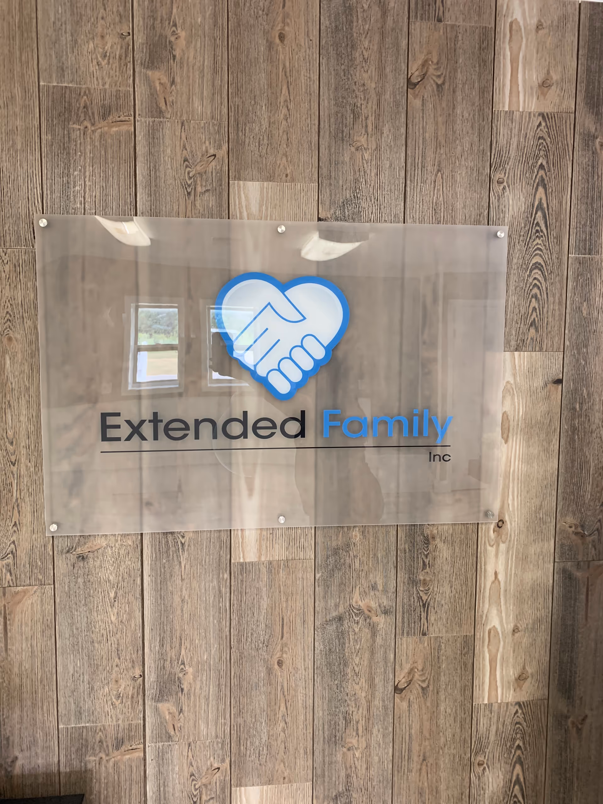 Sign with Extended Family Inc logo mounted on wood-paneled interior wall.