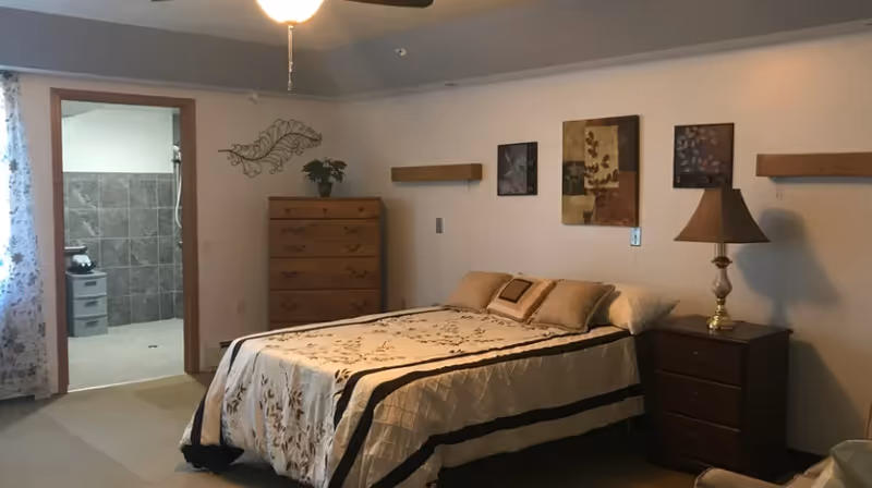 Cozy bedroom with a bed, dresser, nightstands, lamp, ceiling fan, and adjacent bathroom.