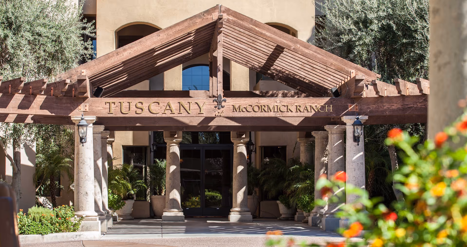 Wooden pergola and stone columns frame the Tuscany at McCormick Ranch entrance.