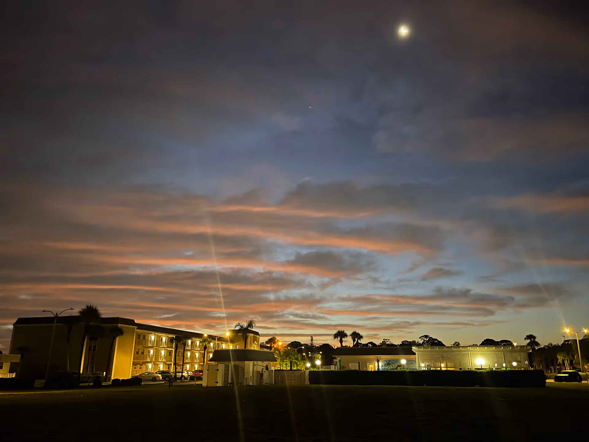 Nighttime exterior of Boca Ciega Point senior living with lit buildings and palms.
