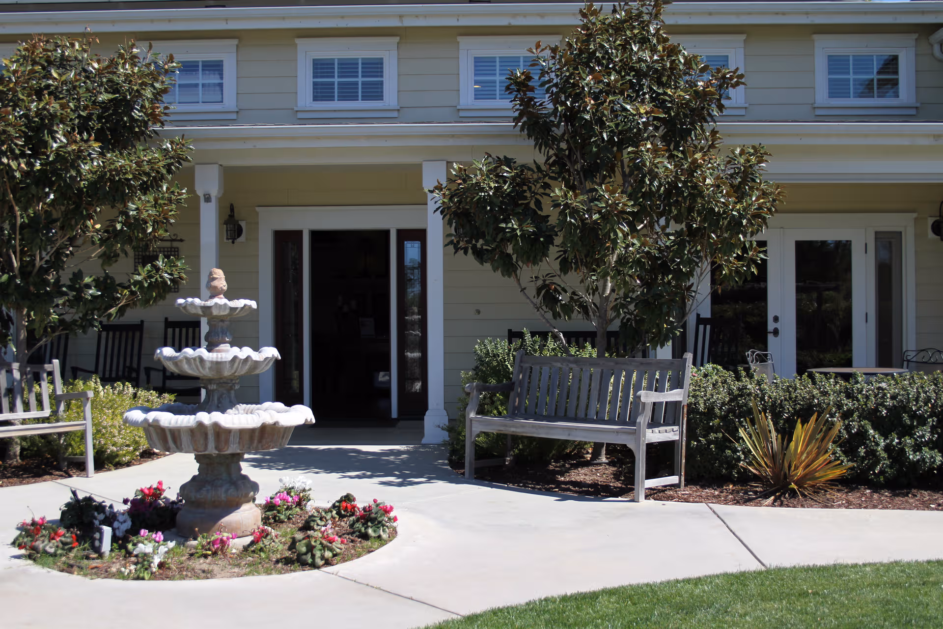 Exterior view of Senior Living Resources facility front entrance with fountain, benches, and landscaping.