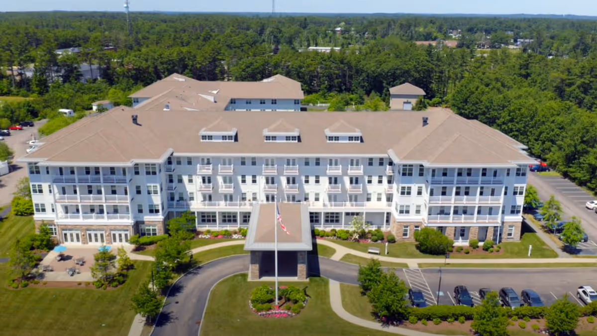 A large multi-story senior living building with beige roof and landscaped grounds.