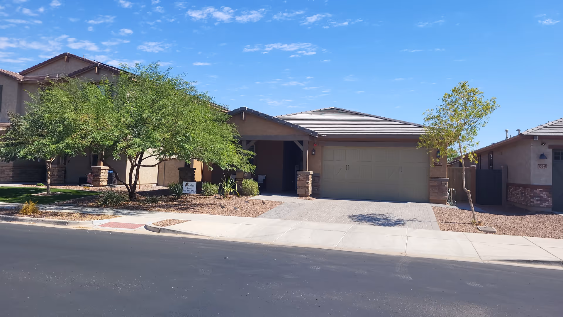 Front view of a single-story assisted living home with a double garage and desert landscaping.