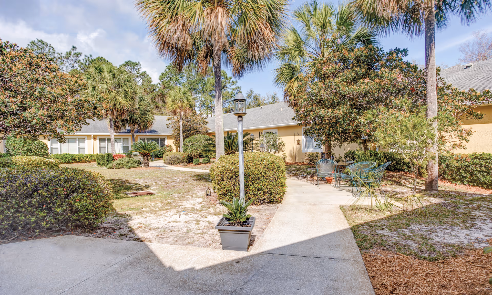 Sunny exterior courtyard of Brookdale Panama City with palm trees and outdoor seating