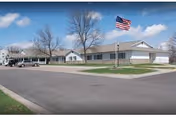 Single-story adult care home exterior with parking lot and American flag.