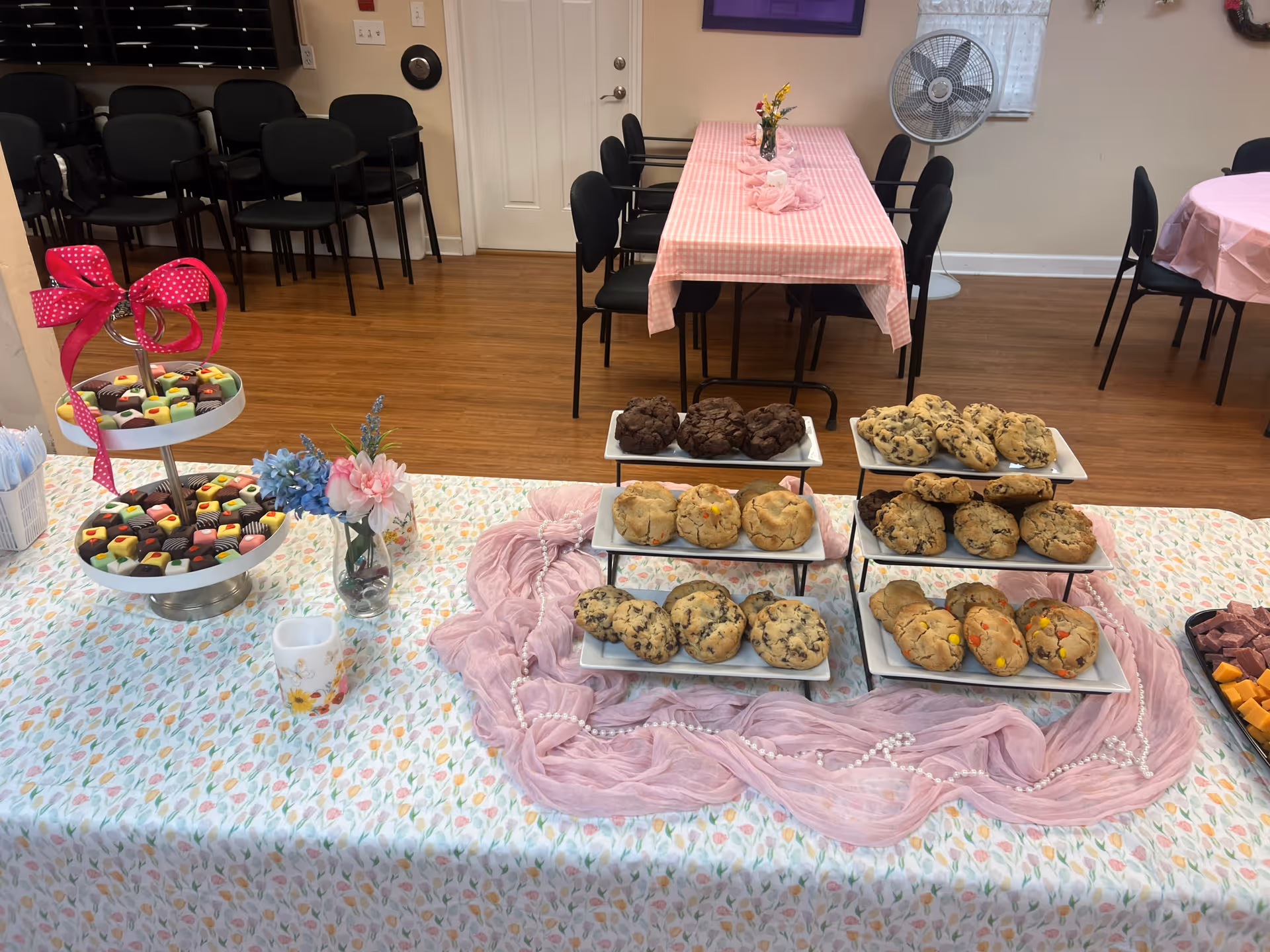 Dessert display with cookies and pastries on pink tablecloths in a dining room.