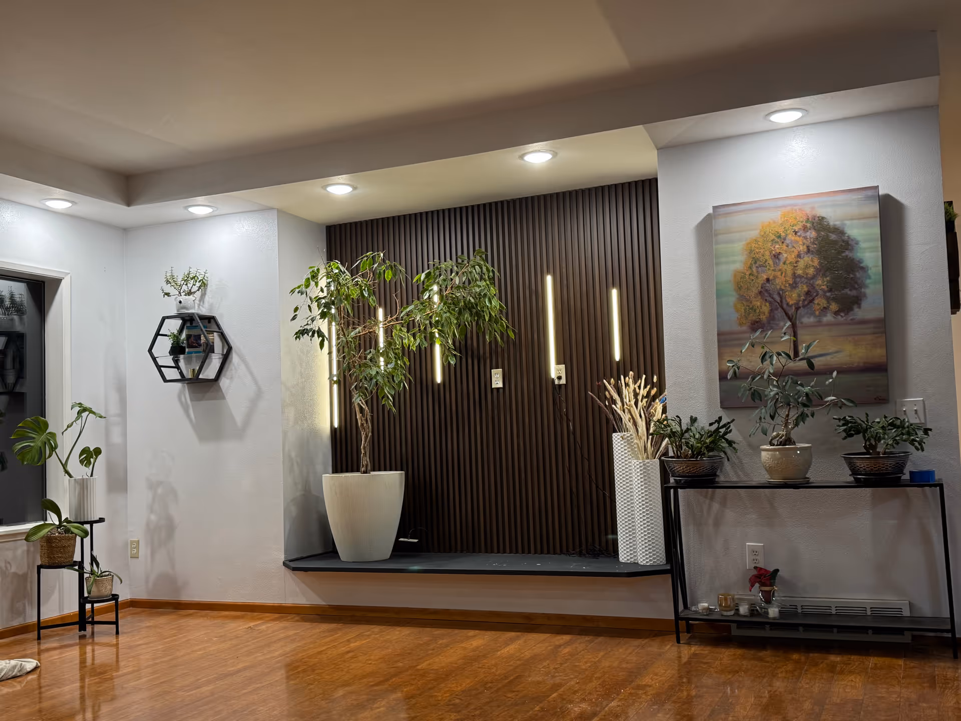 Indoor lobby area with potted plants, wooden floor, and modern wall decor.