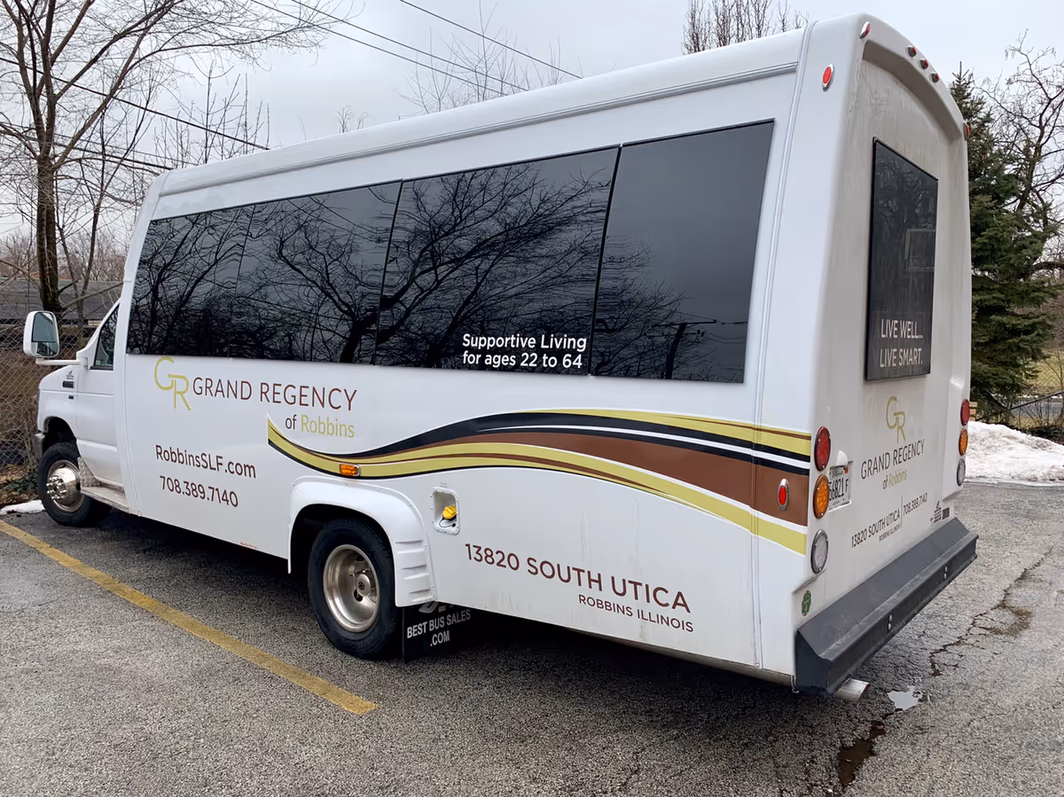 White tour bus branded Grand Regency of Robbins advertising senior living services