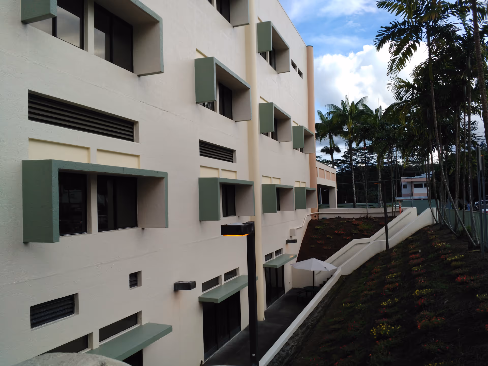 Exterior view of a modern multi-story senior living facility with palm trees and landscaping.