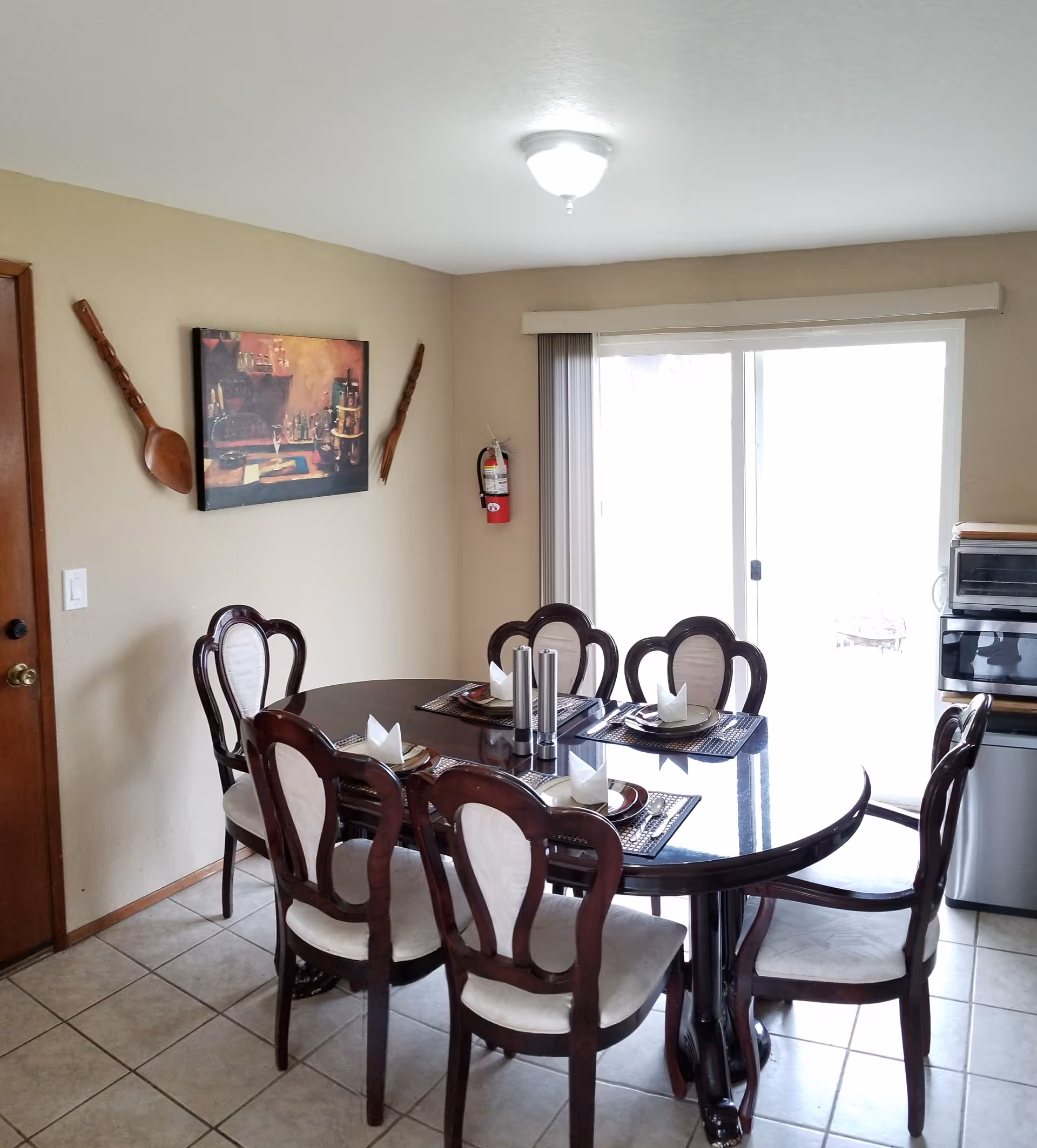 A dining room with a dark wood table, six chairs, and a sliding glass door.