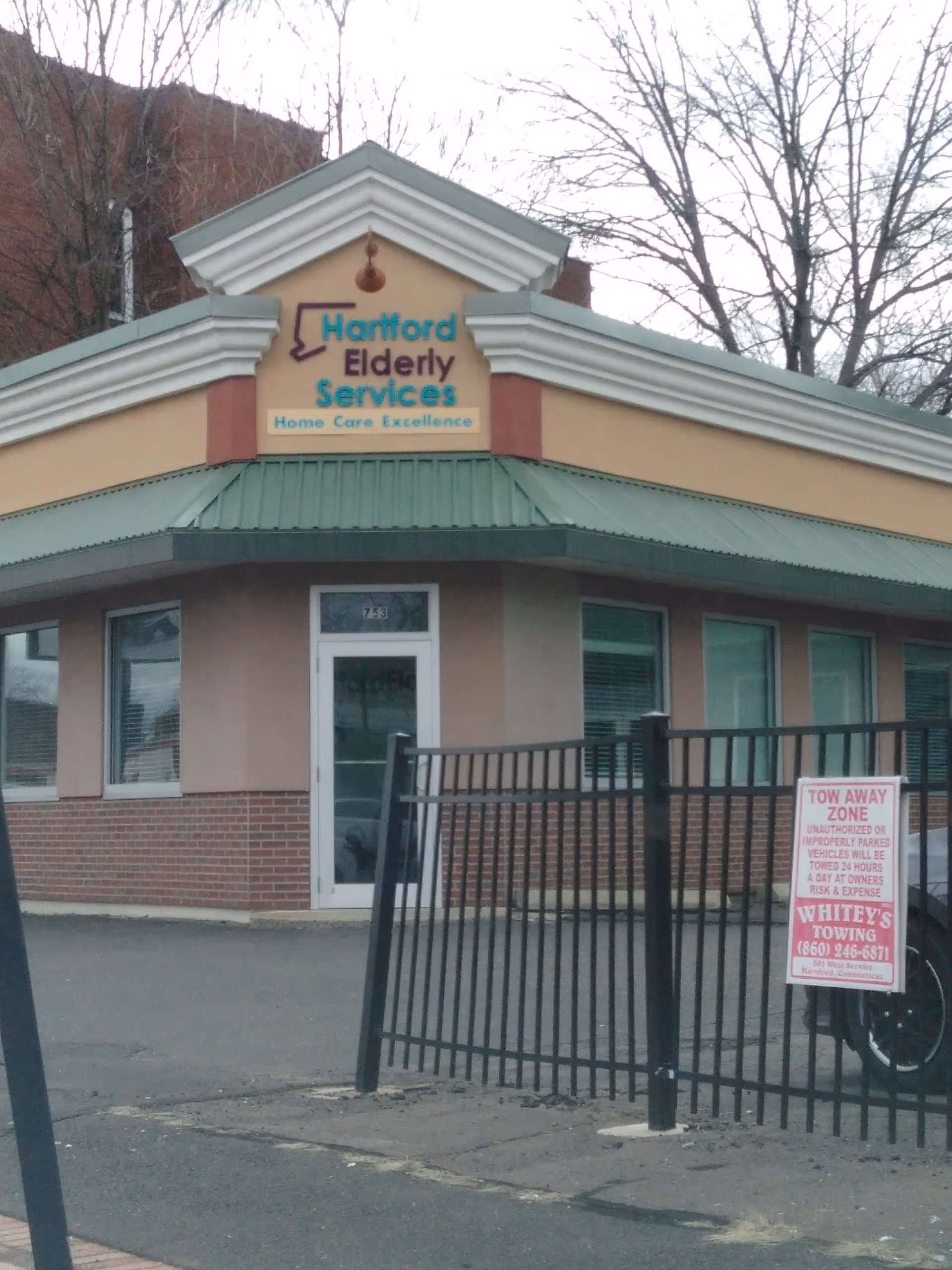 Exterior view of Hartford Elderly Services building with its sign, entry door, and metal fence.