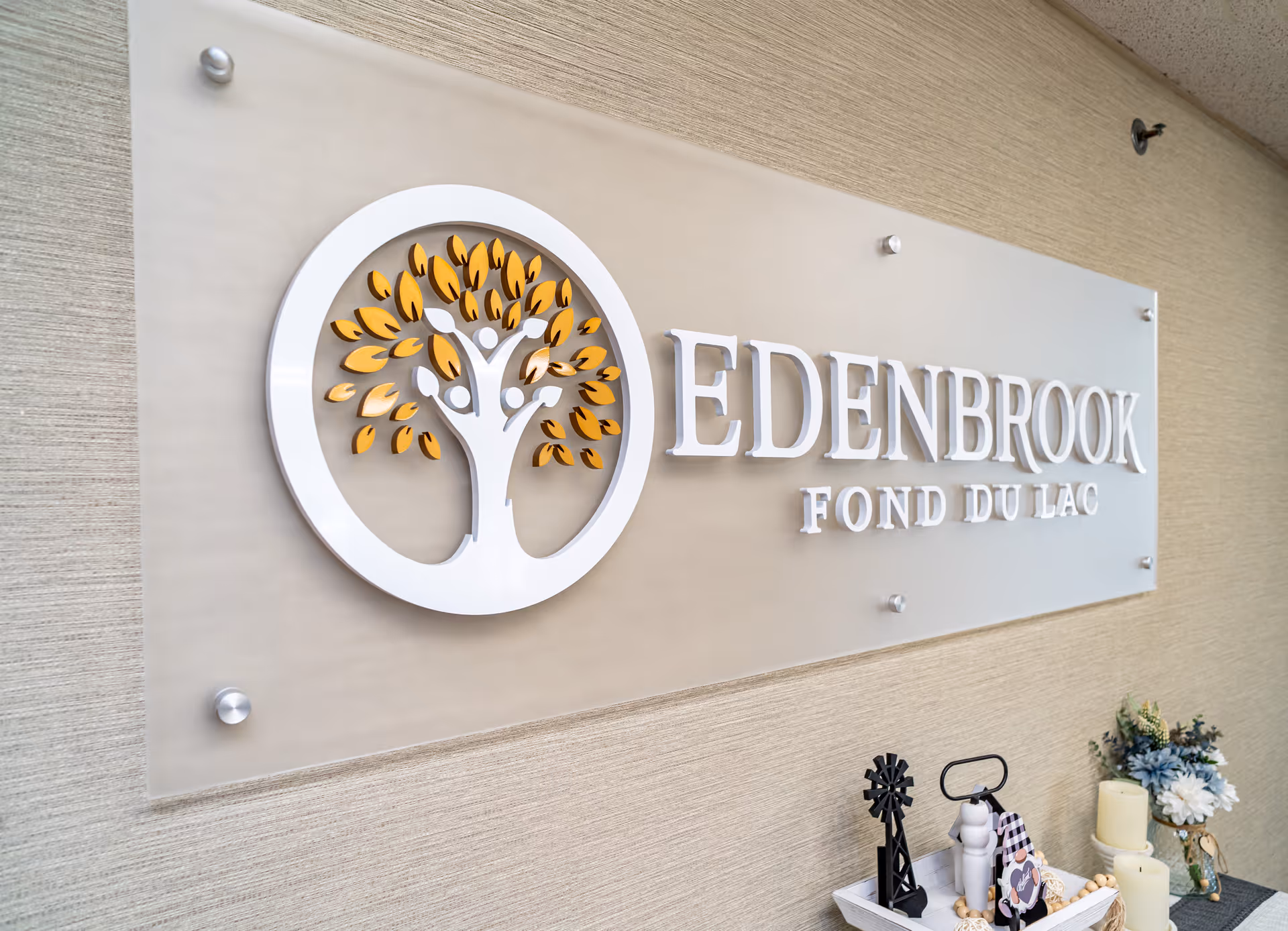 Exterior sign of Edenbrook Fond du Lac with a tree logo on a beige wall