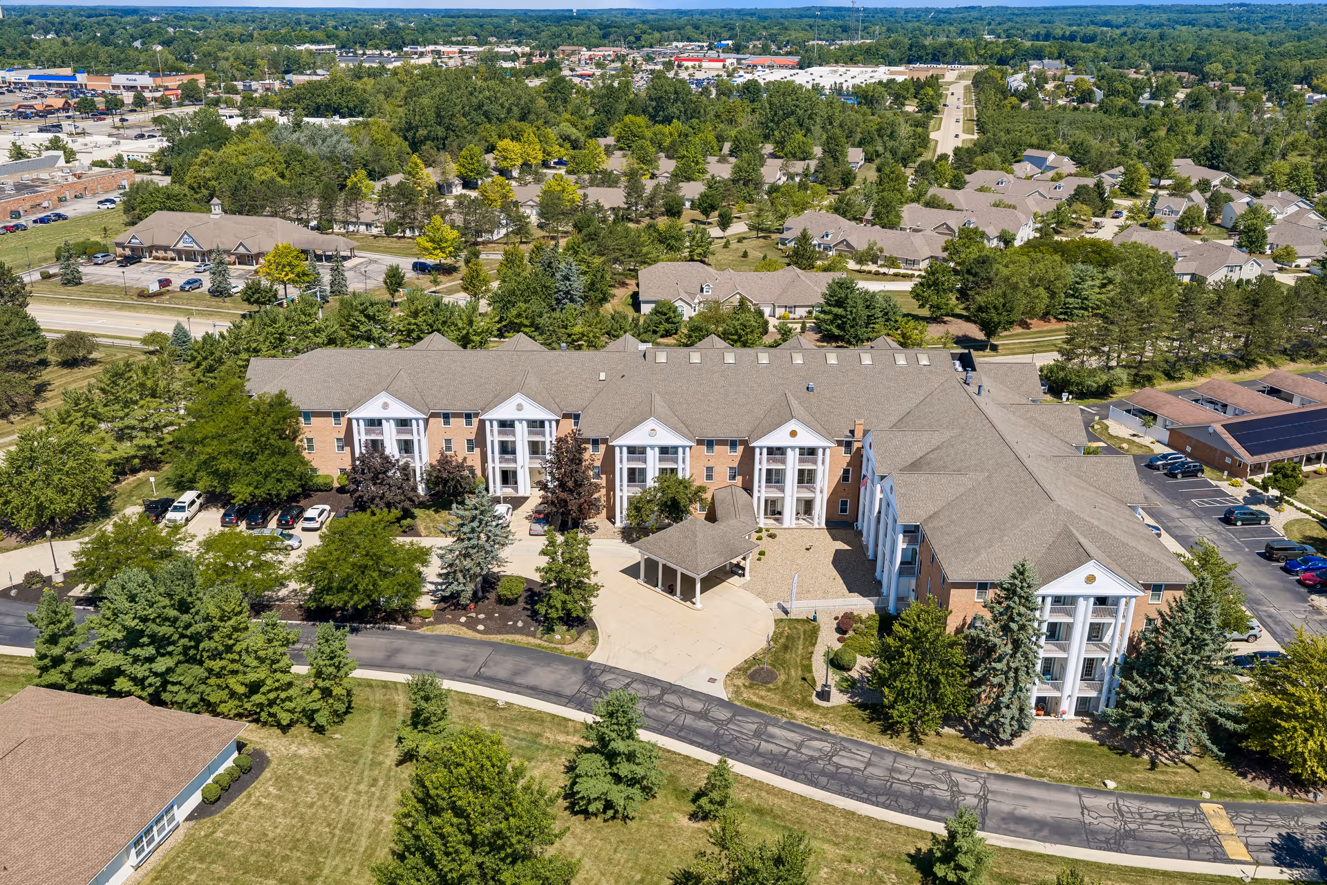 Aerial view of Brookdale Camelot Medina senior living campus with trees and parking.