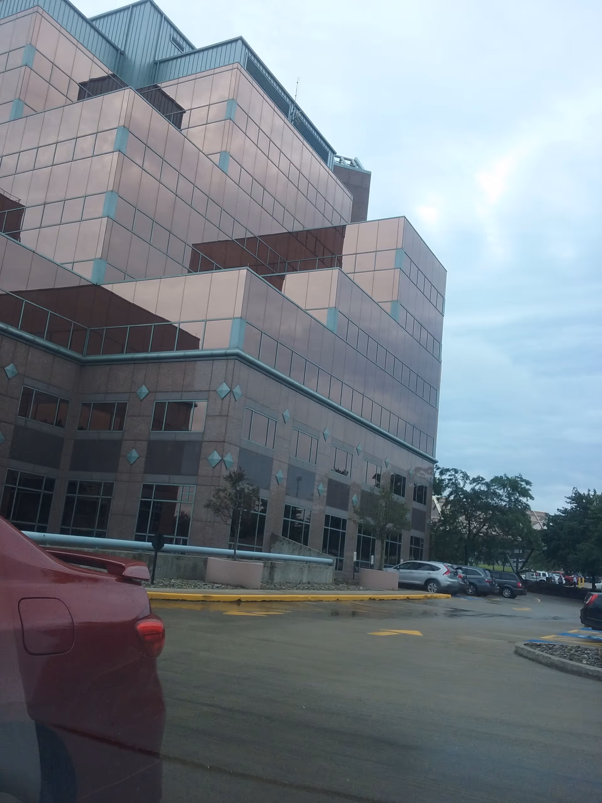 Exterior view of a large multi-story medical building with parked cars