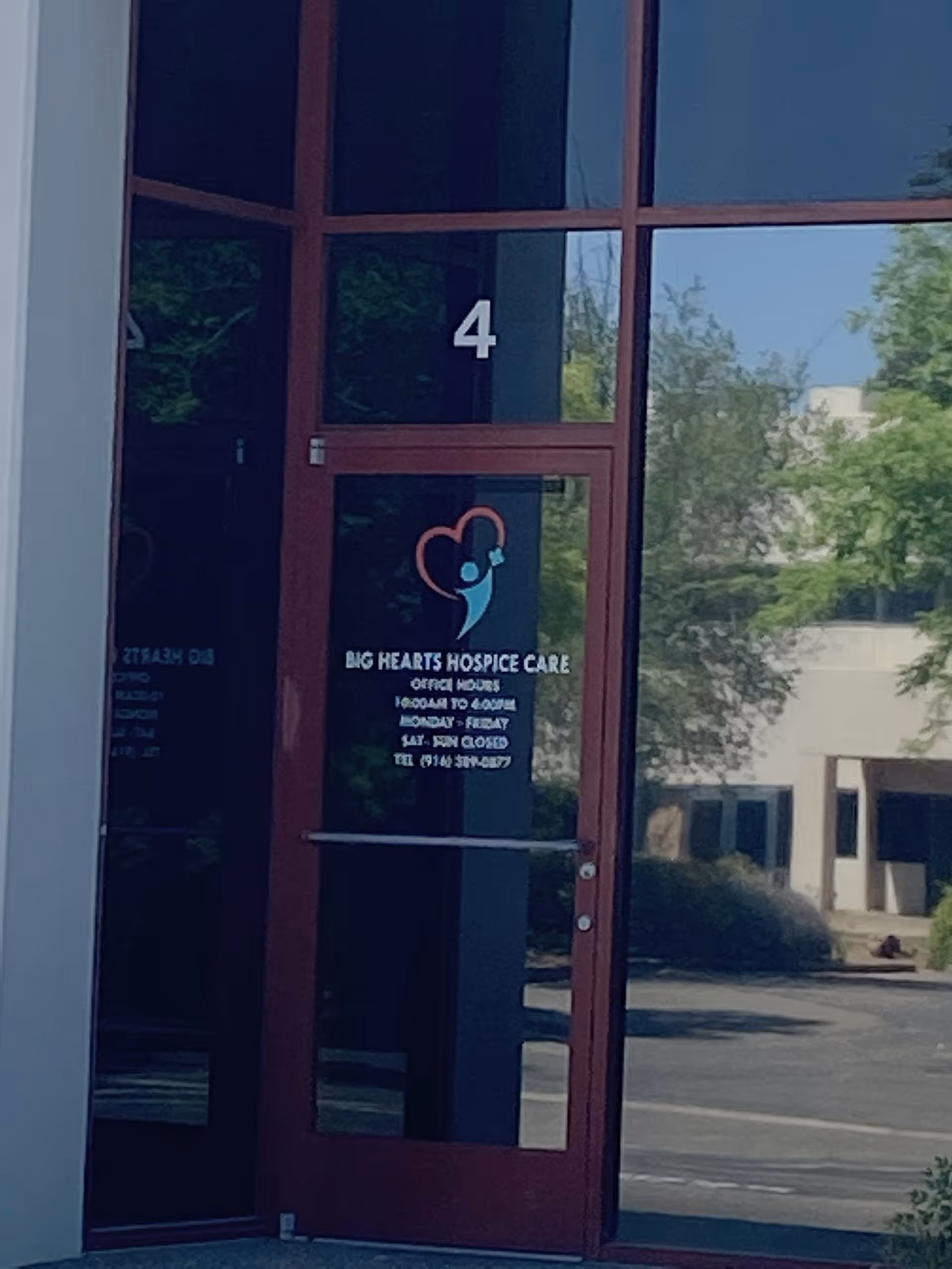 Front entrance of Big Hearts Hospice Care with glass door, 4, and logo.