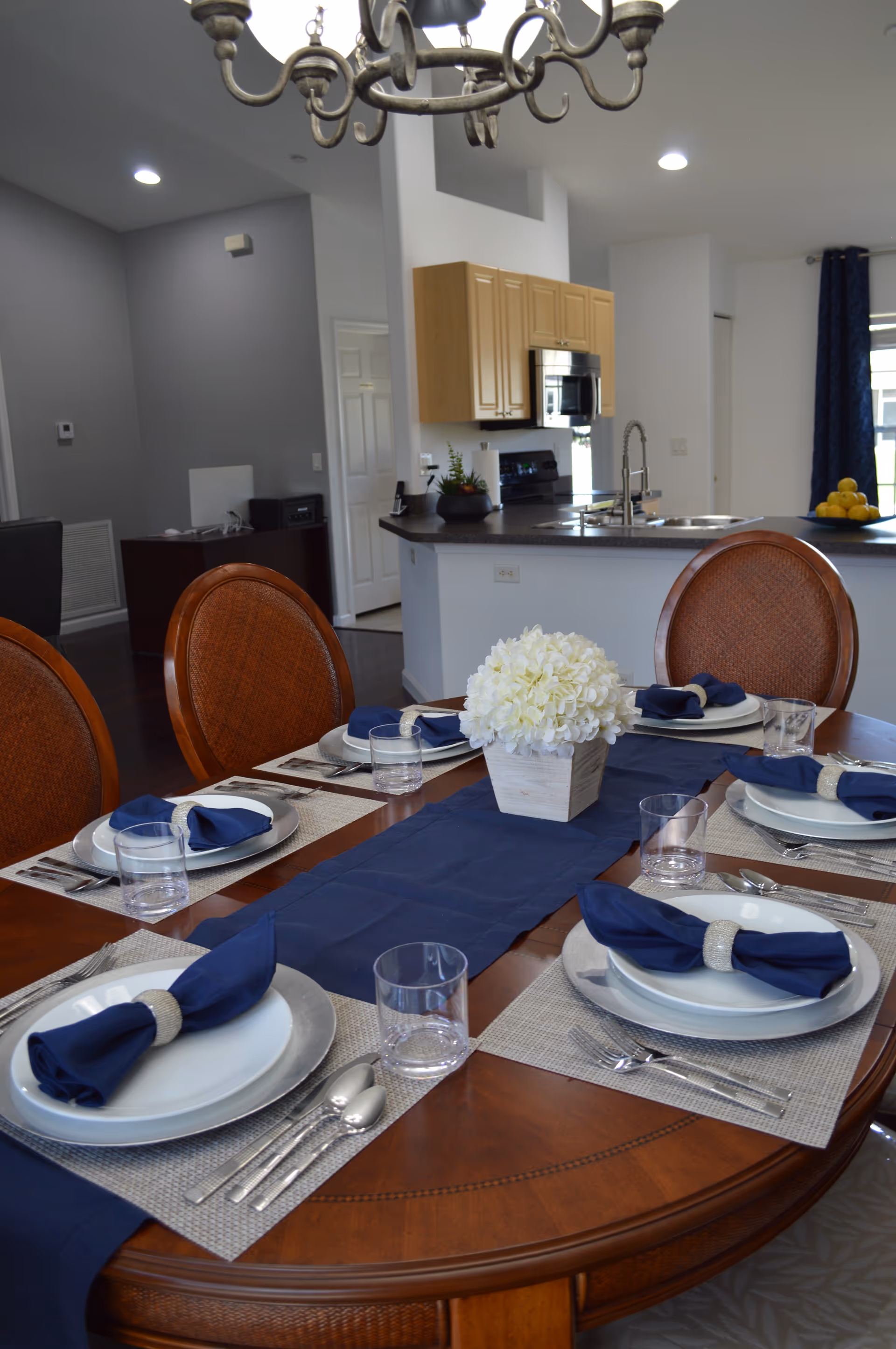 Formal dining table set with navy napkins in a bright open-plan kitchen-dining space.