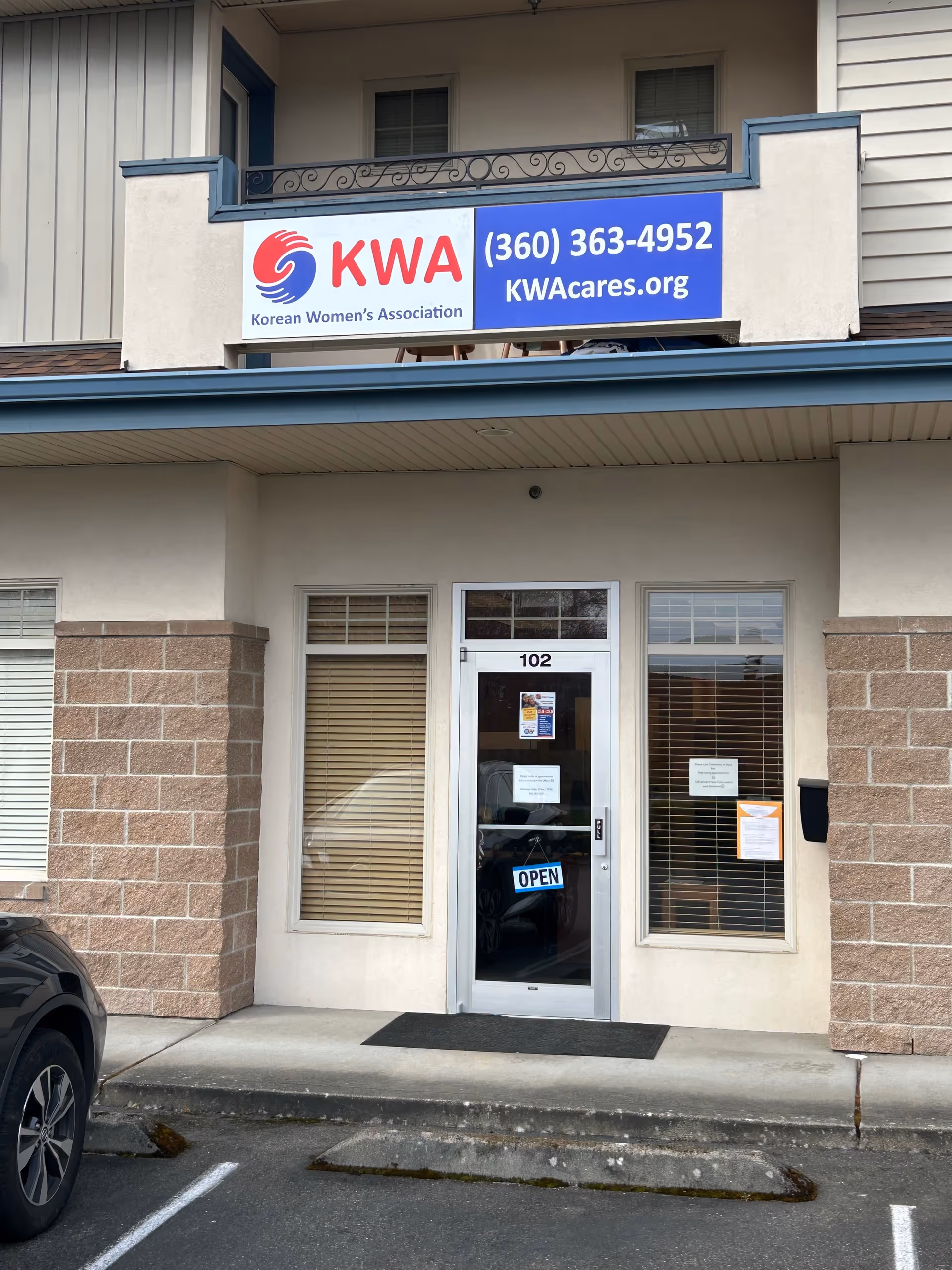 Front entrance of a building with a blue KWA sign and OPEN door.