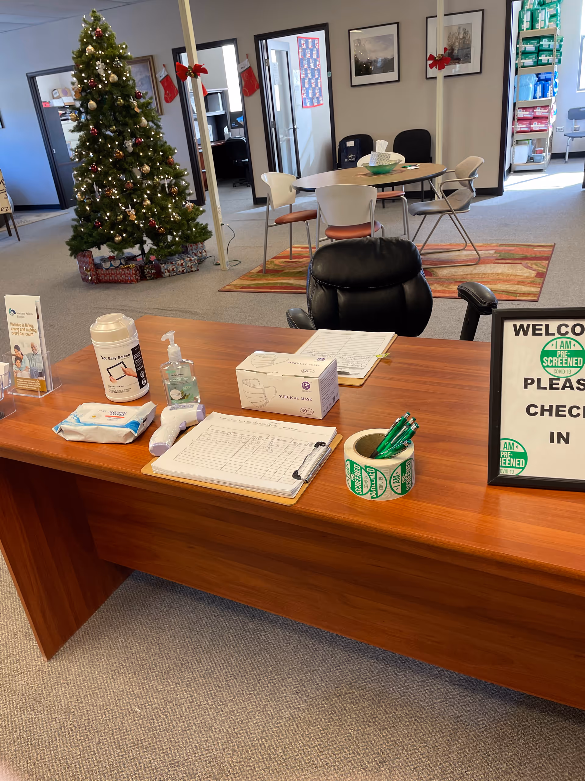 Reception desk in a hospice lobby with a Christmas tree and chairs in the background.