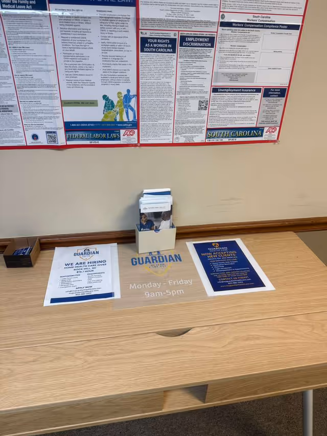 Reception desk with flyers, brochure box, and wall posters in a Guardian Health Care lobby interior.